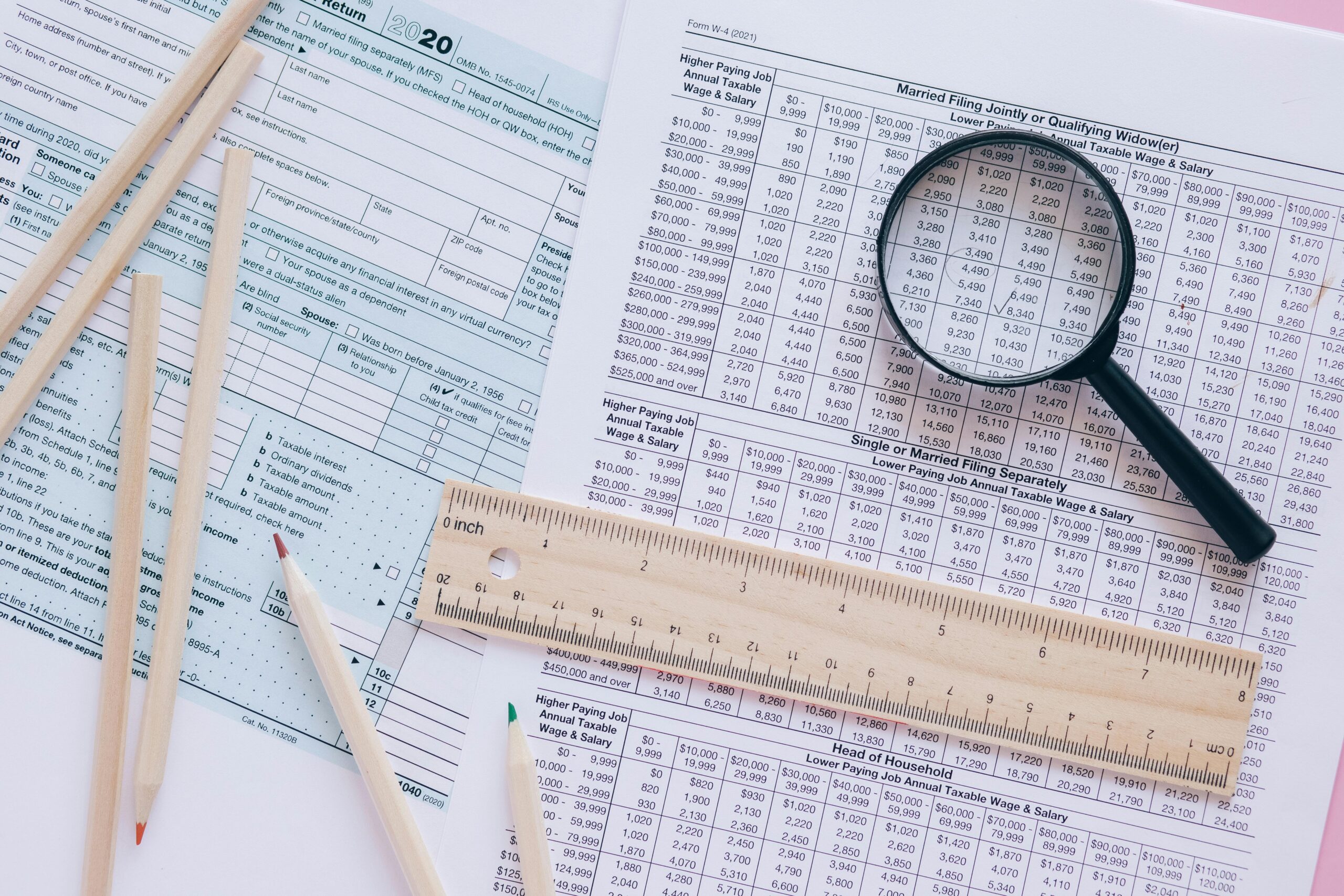 A high angle view showing IRS tax forms with pencils, ruler, and magnifying glass for financial planning.